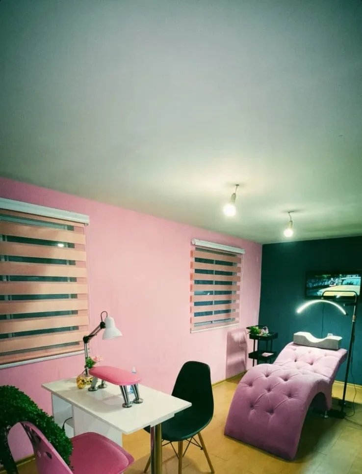 El estudio: mesa de manicure, sillón de pestañas rosado y lámpara de aro